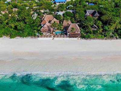 Luftaufnahme von Bungalows am tropischen Strand mit türkisfarbenem Wasser und dichtem Grün.