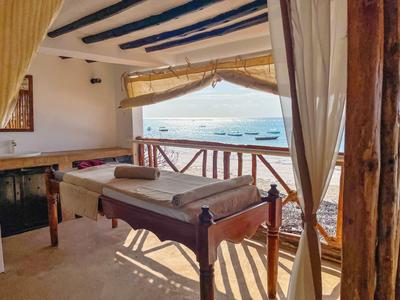 Ein Massagetisch auf einer überdachten Terrasse mit Blick auf das Meer und Boote.