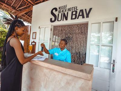 Empfangsbereich eines Strandhotels mit Mitarbeiter und Gast bei der Schlüsselübergabe.