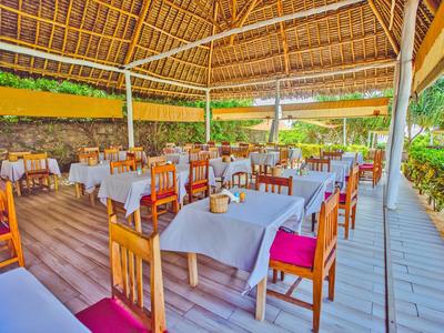 Überdachter Außenbereich eines Restaurants mit Holzböden, Holzmöbeln und weißen Tischtüchern.