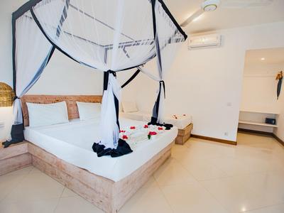 Helles Schlafzimmer mit Doppelbett, Moskitonetz und minimalistischer Einrichtung in warmen Tönen.