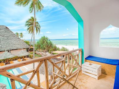 Balkon mit Holzzaun und Sitzbank mit Blick auf Strand, Palmen und Meer bei sonnigem Himmel.