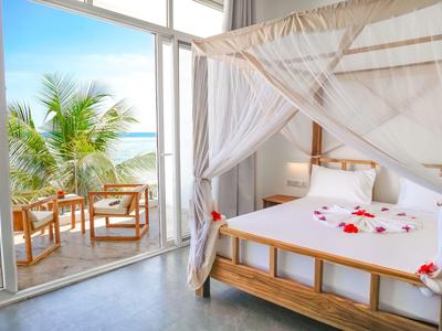 Camera luminosa arredata con letto a baldacchino e balcone con vista sul mare e palme.