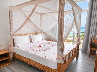 Camera luminosa con letto a baldacchino, biancheria bianca e vista sul mare.