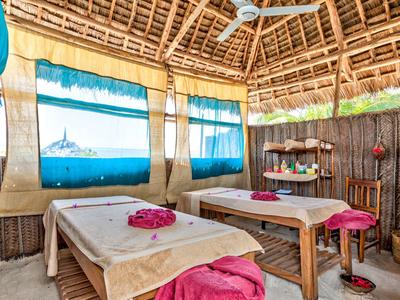 Gemütlicher Massageraum mit zwei Tischen und bunten Vorhängen in tropischer Umgebung.