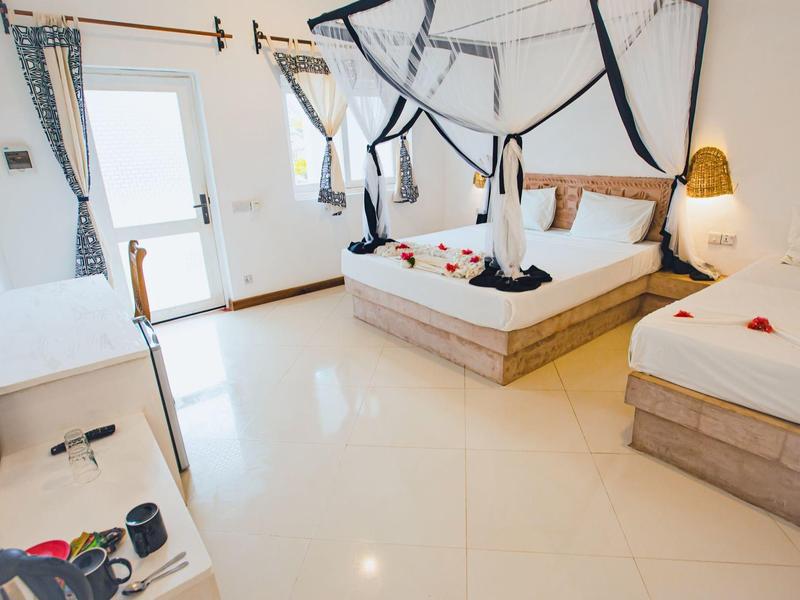 Helles Hotelzimmer mit zwei Betten, weißen Wänden und großen Fenstern.