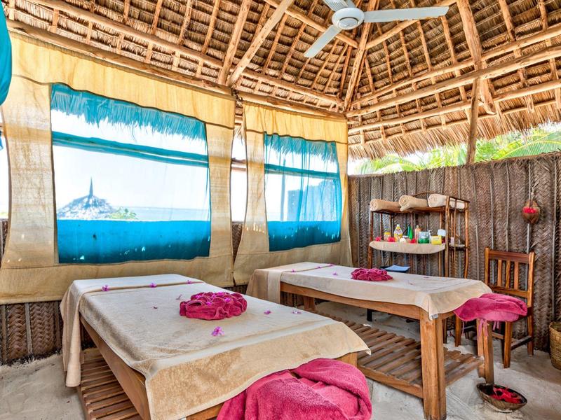 Gemütlicher Massageraum mit zwei Tischen und bunten Vorhängen in tropischer Umgebung.