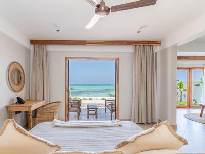 Helles Hotelzimmer mit Blick auf Terrasse und Meer, modern eingerichtet mit hellen Farben.