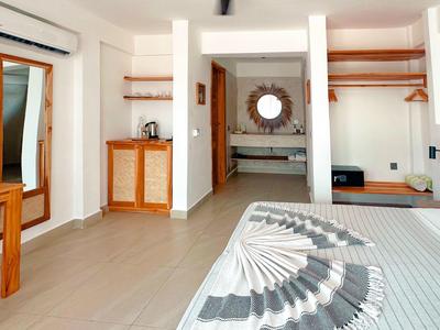 Helles, modernes Hotelzimmer mit Doppelbett, TV, Spiegel und offenem Badezimmerbereich.