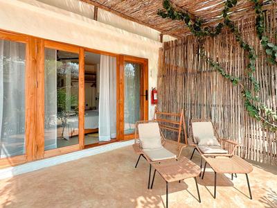 Terrasse mit zwei Stühlen, Holzrahmenfenstern und einer mit Pflanzen bedeckten Wand.