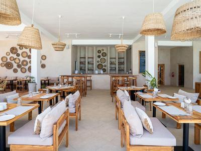 Helles Restaurant mit Holzmöbeln, Korbhängelampen und dekorativen Wandobjekten.