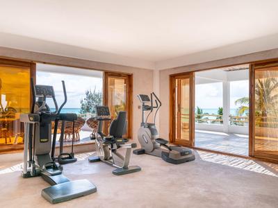Gimnasio con equipo moderno y grandes ventanas con vistas a la terraza y el mar