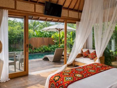 Gemütliches Zimmer mit Himmelbett, bunter Tagesdecke und Blick auf Pool und Garten.