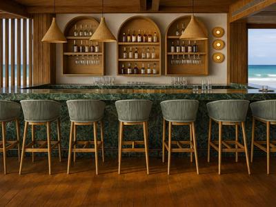 Elegante Hotelbar mit grünen Barhockern, marmoriertem Tresen und Blick aufs Meer.