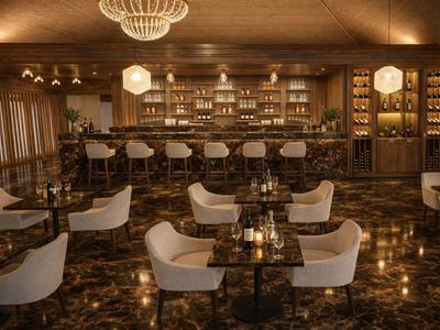 Elegante Hotelbar mit weißen Sesseln, großem Holztresen und warmem, gemütlichem Licht.