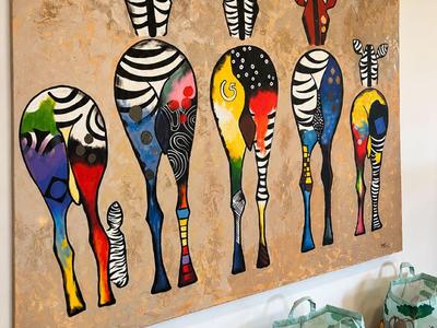 Bunte Zebras mit verlängerten Beinen an einer Wand in einem Hotelzimmer, Holzfußboden sichtbar.