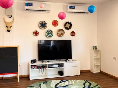 Moderner Hotelzimmerbereich mit dekorativen Lampions, TV und buntem Teppich auf Holzboden.
