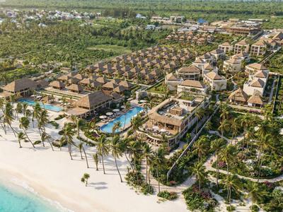 Großes Strandresort mit Mehrfamilienbungalows, Pools und umliegender tropischer Vegetation am Meer.