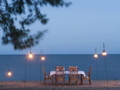 Eleganter Esstisch mit Stühlen auf einer Terrasse mit Blick auf das Meer bei Sonnenuntergang.