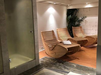 Nowoczesna strefa wellness z drewnianymi leżankami i uspokajającym oświetleniem.