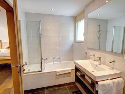 Modernes Badezimmer mit Badewanne, Dusche und Waschbecken, Blick ins Schlafzimmer
