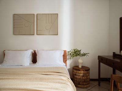 Schlichtes Schlafzimmer mit Doppelbett, zwei Kissen, Beistelltisch und Wandkunst.